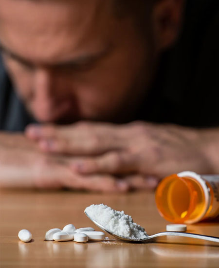 Таблетки и порошок на столе перед мужчиной